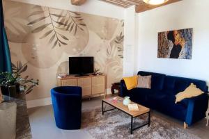 uma sala de estar com um sofá azul e uma televisão em Appartement provençal tout confort dans le Var em Les Arcs sur Argens
