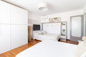 Habitación blanca con 2 camas y TV. en Attico Centralissimo Vista Mare, en Torvaianica