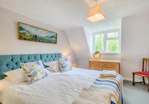 Schlafzimmer mit einem großen weißen Bett mit blauem Kopfteil in der Unterkunft 2 The Homestead in Frostenden