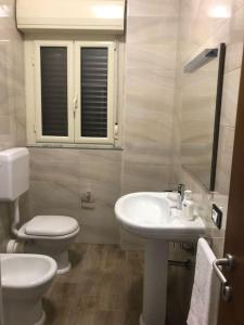 a white bathroom with a toilet and a sink at Casa Narciso - Mondello in Mondello