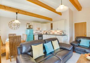 a living room with a leather couch and a kitchen at Gorwel in Abersoch