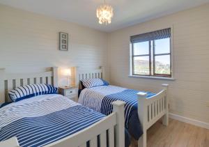 a bedroom with two beds and a window at Gorwel in Abersoch