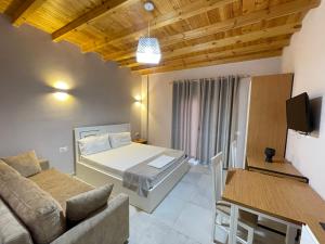 a bedroom with a bed and a couch and a tv at Maison Apartments in Vlorë