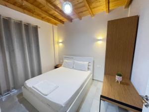 um quarto com uma cama branca e um tecto de madeira em Maison Apartments em Vlorë