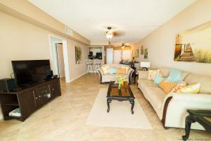 a living room with a couch and a tv at Gorgeous Ocean Views! Welcome to Bella Breeze! BeachFront 2BR 2BA in Sion Farm