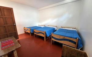 a room with two beds and a door and a table at Peru Hostel Inn Plaza in Cusco