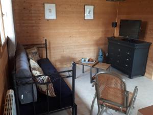 a room with a bed and a tv and a couch at LE CHALET in Saint-Pierre-dʼArthéglise