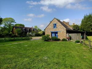 una casa de ladrillo con un césped verde delante de ella en Roulottes des Trolls, en La Boussac