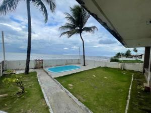un patio trasero con piscina junto al océano en Casa de Praia Pitimbu en Pitimbu