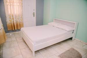 a white bed in a room next to a door at Happy Holidays Style Residences in Paramaribo