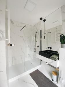 a white bathroom with a shower and a sink at powiew in Świnoujście