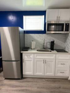 La cuisine est équipée de placards blancs et d'un réfrigérateur en acier inoxydable. dans l'établissement Marvelous Modern apartment at perfect location, à Mount Vernon
