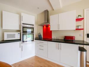 a kitchen with white cabinets and a red refrigerator at The Barn at Courtleigh in Kingsbridge +3 photos