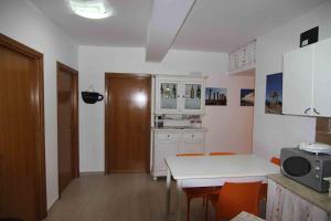 a kitchen with a white table and orange chairs at B&B Le Dune Beach in San Leone