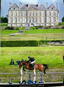 VimoutiersにあるBleu D'Orageの大きな建物前に馬に乗る男