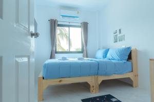a bed in a blue room with a window at Phanomrung Hostel & Linn Chan Cafe พนมรุ้ง โฮส์เทล แอนด์ ลิณณ์จัง คาเฟ่ in Buriram