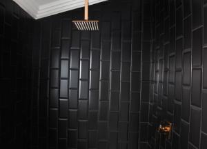 un bagno con pareti piastrellate di nero e lampadario. di 4447 Guesthouse a Pimville