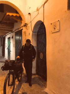 a man standing in front of a building with a bike at Tarbi'aat Tetaoun 44, 17th century heritage in Tétouan