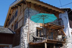 a blue umbrella on a balcony next to a building at Appartement Dans Chalet de Montagne in Bozel