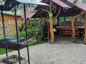 a grill in a pavilion with a table and a bench at Марічка Marichka in Vorokhta +34 photos
