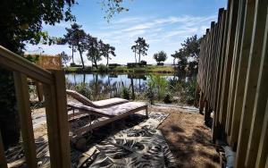 un banco sentado junto a una valla junto a un lago en Le Bungalow du Ferret - Mobil Home Premium en Claouey