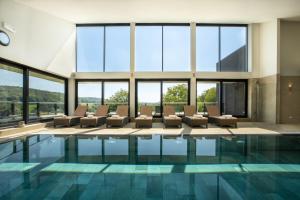 uma casa com piscina com cadeiras e janelas em Klein Zwitserland em Slenaken
