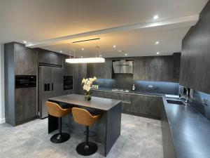 Newly refurbished 4 Bedroom House-Sleep 8-Free parking في Canvey: مطبخ مع طاولة وبعض الكراسي الزرقاء