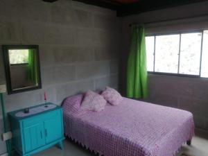 a bedroom with a purple bed and a window at Soki in Guatapé