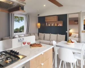 eine Küche und ein Wohnzimmer mit Sofa und Tisch in der Unterkunft Le Bungalow du Ferret - Mobil Home Premium avec vue bassin d'Arcachon in Claouey + 8 Fotos