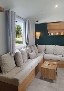 ein Wohnzimmer mit einer Couch und einem Fenster in der Unterkunft Le Bungalow du Ferret - Mobil Home Premium avec vue bassin d'Arcachon in Claouey
