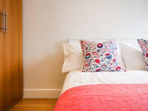 a bed with a red blanket and two pillows on it at The Barn at Courtleigh in Kingsbridge