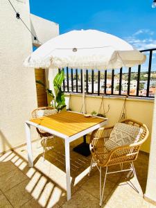 a table and chairs with an umbrella on a balcony at Caparica Rooftop Beach Apartment in Costa da Caparica