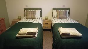 two beds in a bedroom with green sheets and towels at Bowtree House Bed and Breakfast in Grantham