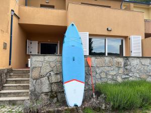una tabla de surf azul apoyada en una pared de piedra frente a una casa en Casa d´Água en Venda Nova