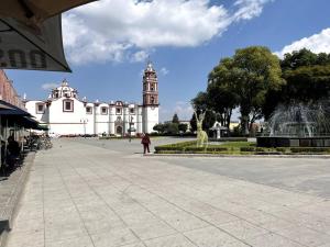 una persona in piedi di fronte a un edificio con una torre dell'orologio di Corazon de San Pedro Cholula a Cholula Altre 9 foto