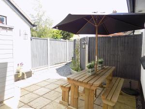 ein hölzerner Picknicktisch mit einem Sonnenschirm auf einer Terrasse in der Unterkunft Double Award Winning 1700's Grd 2 listed cottage near Stonehenge in Amesbury