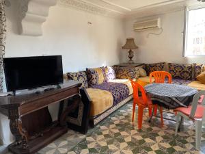 a living room with a couch and a table with a tv at Au cœur du Médina in Fez