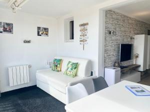 un soggiorno bianco con divano bianco e TV di Appt Climatisé Vue Mer Club P&V Restanques Golfe de Saint-Tropez - Les Roses - Grimaud a Grimaud
