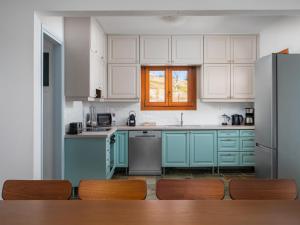 een keuken met blauwe kasten en een koelkast bij Villa Aura Pine in Agia Pelagia