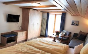 1 dormitorio con 1 cama, TV y mesa en Gästehaus Luitz-Kennerknecht, en Fischen