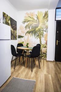 een tafel en stoelen in een kamer met een muurschildering van palmbomen bij The Tropical House Tirana in Tirana
