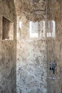 een badkamer met een douche en een stenen muur bij The Tropical House Tirana in Tirana