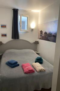 un letto con due asciugamani sopra con una finestra di Appt Climatisé Vue Mer Club P&V Restanques Golfe de Saint-Tropez - Les Roses - Grimaud a Grimaud