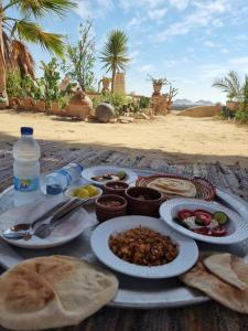 a table topped with plates of food on a beach at ECO ROOMS Siwa in Siwa