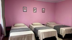 Duas camas num quarto com paredes cor-de-rosa em Pousada Mercosul em Alegrete