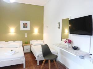 a room with two beds and a desk with a tv at Apartments Papadioti in Pefki
