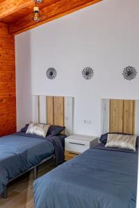 two beds in a room with wooden walls at Casas Cristea in Cehegín