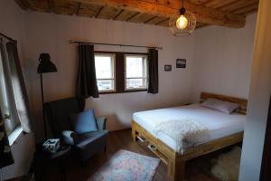 a bedroom with a bed and a chair and a window at Drevenica Harmony so saunou in Ružomberok