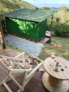 uma cadeira e uma mesa num deque com um contentor verde em Alto da Villa em Ouro Preto