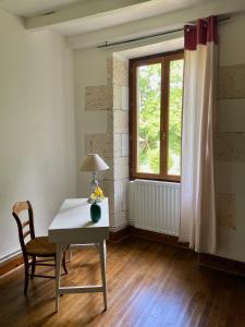 a table and a chair in a room with a window at La Colline aux Licornes in Montbron